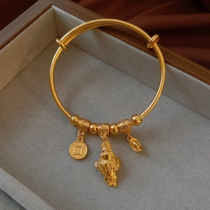 Detail view of gold-plated bracelet with Buddha, coin and ingot charms in a jewelry box