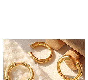 Detailed view of chunky 18K gold plated minimalist rings on white knitted fabric
