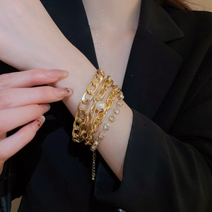 Detail of a four-layer gold chain bracelet set with pearl and rhinestone accents on wrist
