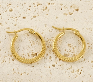 Detailed macro view of gold hoop earrings with radial relief texture on stone surface
