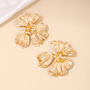 Macro shot of gold metal flower earrings with irregular texture and pearl stamen detail