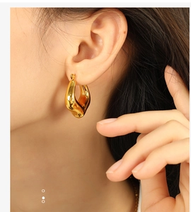 Detail shot of gold geometric twist C-shape earrings with a polished mirror finish