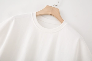 Gros plan sur la texture du t-shirt blanc et le col rond sur un cintre en bois