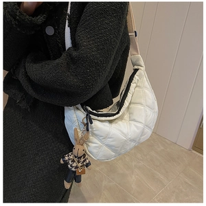 Close-up of quilted crescent crossbody bag with detailed stitching and rabbit charm