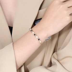 Gold evil eye heart bracelet for women featuring black and white enamel heart charms