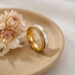Détail de la bague en acier doré avec incrustation de coquille blanche et maille tressée