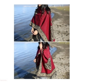 Close-up of red shawl with ethnic paisley patterns and fringe tassels in outdoor setting