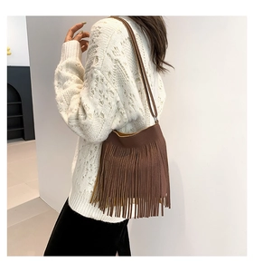 Close-up of brown fringe tassel shoulder bag with lychee texture on a model outfit