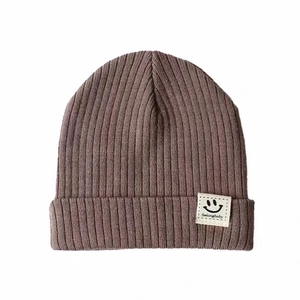 Purple ribbed knit baby beanie with a white smiley face patch for winter warmth