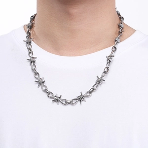 Detailed close-up of a silver thorn chain necklace in punk style on a model neck