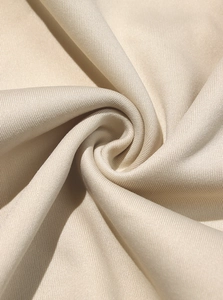 Dettaglio macro della trama del tessuto pile beige con morbide pieghe a spirale