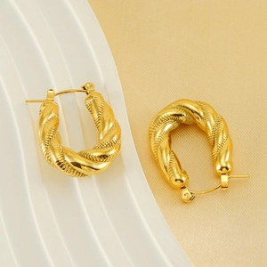 Vintage 18K gold plated U-shaped twist earrings with textured relief on white props