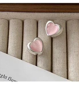 Close-up of pink heart stud earrings with cat-eye gemstone in beige velvet box