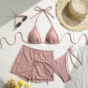 Detailed flat lay of a dusty pink three-piece lace bikini set with matching beach shorts