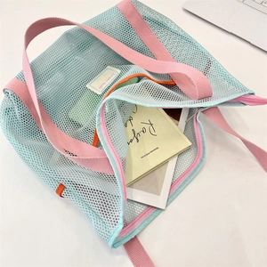 Detail of mint green mesh beach bag with pink handles and secure zipper closure