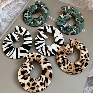 Detailed view of spiral fabric earrings featuring camouflage, zebra, and leopard prints