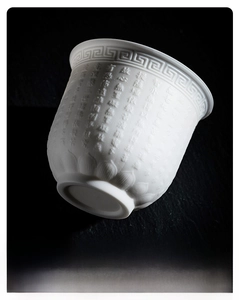 Macro detail of Dehua white porcelain tea cup with embossed Heart Sutra and lotus texture