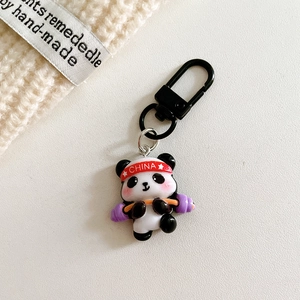 Detail of cute panda weightlifting keychain in resin with red and purple sports accents