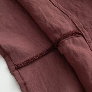 Macro view of dark reddish-brown sheer blouse with detailed edge stitching and fine texture