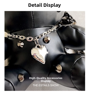 Close-up of punk style black leather bear bag with silver rivets and heart pendant