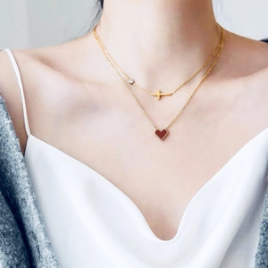 Elegant double-layered gold necklace featuring a red heart pendant and horizontal cross