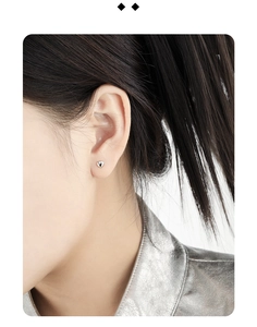 Close-up of minimalist heart stud earring in silver on female model's ear