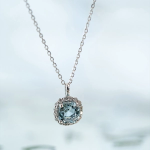 Macro view of square aquamarine pendant with diamond halo on silver chain necklace