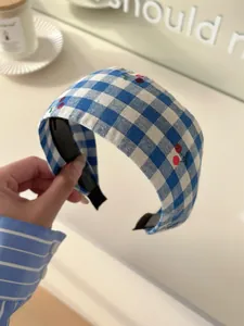 Detail of blue and white plaid headband with small cherry prints and anti-slip teeth
