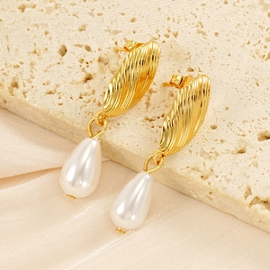 Dettaglio di orecchini dorati con texture a conchiglia e perle a goccia eleganti