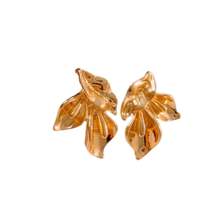 Boucles d'oreilles géométriques dorées en forme de lys calla sur un fond blanc neutre