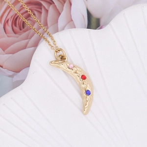 Close-up of gold crescent moon pendant with textured finish and three colored gemstones
