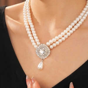 Detail of double-layer pearl necklace with silver rhinestone teardrop pendant on model