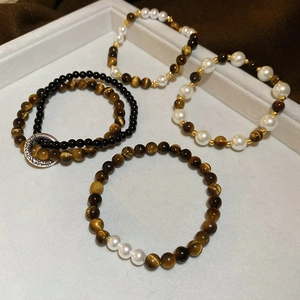 Detail of tiger eye and pearl beaded bracelets set with silver carved metal rings