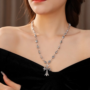 Close-up of vintage silver necklace with floral links and a stylized cross pendant detail