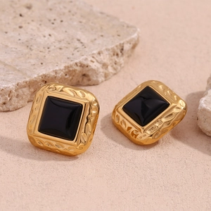Detail of vintage square gold-plated stud earring with black acrylic inlay and hammered texture