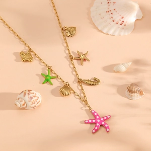 Detailed view of gold ocean charms with starfish and shells on a peach backdrop