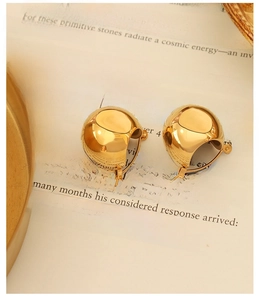 Close-up of polished gold U-shaped earrings on an open book showing glossy mirror finish