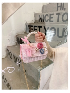 Detail of pink tweed girl bag with pearl handle, plush bunny charm and chain strap
