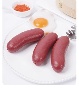 Detailed realistic artificial roasted sausages and fried egg on a white plate decor