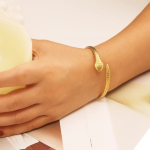 Detail of gold snake cuff bracelet featuring scale textures and open-end design