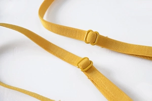Detail of adjustable bright yellow lace bra strap with high elasticity and matching slider