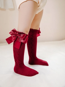 Detail of dark red cable-knit knee-high socks with double bows for toddler girls