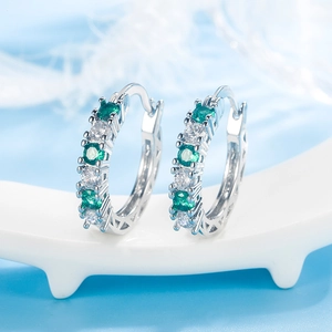 Silver hoop earrings featuring emerald green and white round-cut stones with hollow design