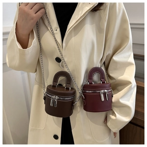 Détail de mini sacs cylindres en marron foncé et bordeaux avec des chaînes argentées