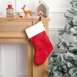 Detail of red and white plaid Christmas stocking with embroidered elk on a cozy fireplace