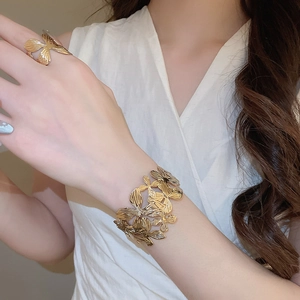 Dettaglio del bracciale rigido a fiori cavi e anello regolabile coordinato in oro