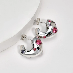Modern C-shaped silver earrings with colorful pink and purple zircons on white backdrop