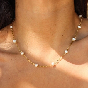 Close-up of elegant gold chain necklace with natural freshwater pearls on model neck