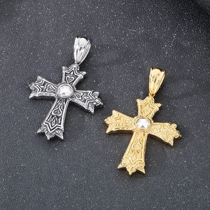 Détail de pendentifs croix punk argent et or avec motifs en relief et pierres centrales