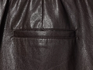 Detailed macro view of the premium brown faux leather fabric and pocket stitching